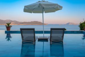 two chairs and an umbrella next to a swimming pool at Hamarat Otel in Kaş