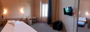 a hotel room with a bed and a television at Hôtel des Pyrénées in Angoulême
