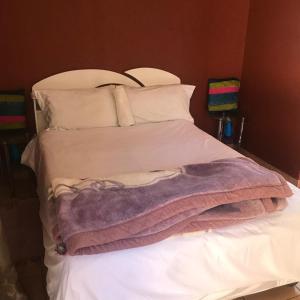 Una cama blanca con una manta morada. en MONGILO GUESTHOUSE, en Windhoek 6 fotos más