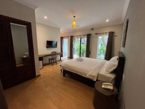 a bedroom with a bed and a desk and a television at Angkor Daji Boutique in Phumĭ Réach Born