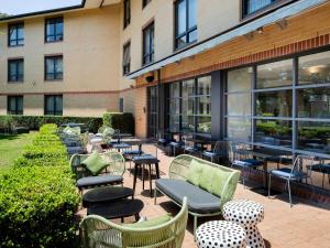 悉尼Mercure Sydney Macquarie Park的大楼前带桌椅的天井