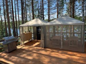 a gazebo with a grill on a deck at Tree Tents Camping Linnansaari in Savonlinna