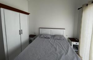 a bed in a white room with a striped mattress at Canterbury Golf Resort Apartments in Kahatuduwa