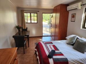 een slaapkamer met een bed, een bureau en een tafel bij Cape Cottage in Kaapstad