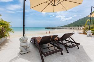 a table and chairs and an umbrella on a beach at Beachfront 4BR Villa with Private Pool - Ocean Access in Chaloklum