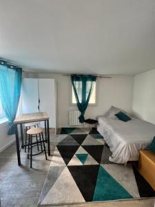 a bedroom with a bed and a desk and a table at Studio Cozy proche aéroport CDG in Claye-Souilly