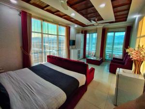 a bedroom with a large bed and large windows at Swat Hilton Hotel by Khan Familia in Swat