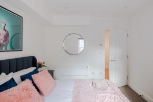 a bedroom with a bed with pink and blue pillows at The Vanity Affair - Fitzrovia - By Frankie Says in London