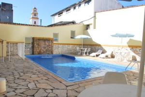 a pool with chairs and a building with a clock tower at Hotel Aliança in São Lourenço