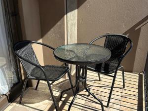 a glass table and two chairs on a patio at Cozy In Jozi Accommodation in Edenvale +4 photos