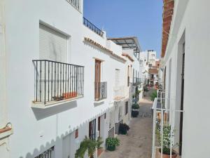 an alley with white buildings and potted plants at Noctua Estepona Old Town 025 in Estepona