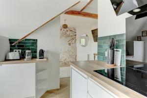 een keuken met witte kasten en groene tegels bij Le Gresset - Vanves in Vanves