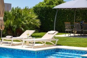 a pool with two white lounge chairs and an umbrella at Sunny Garden Lux in Split