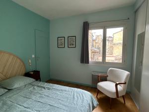 a bedroom with a bed and a chair and a window at Cocon dans le centre in Bordeaux