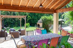 un patio con tavolo e sedie sotto un pergolato di Vila nostra familha a Vallon-Pont-dʼArc
