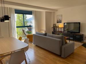 ein Wohnzimmer mit einer Couch, einem Fernseher und einem Tisch in der Unterkunft Ventanal de Saras Petfriendly Garaje Trastero y Chimenea - Arafita Apartamentos in Panticosa