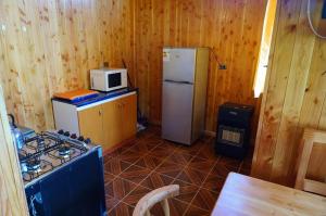 a kitchen with a refrigerator and a microwave at Lican Ray Cabañas Los Primos in Licán Ray