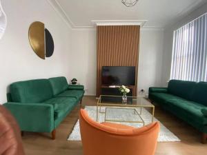 a living room with green couches and a tv at 3-Bed House Near M1 & Meadowhall with Free Parking in Sheffield