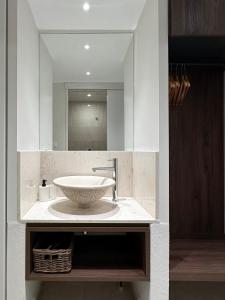 a bathroom with a sink and a mirror at Zouzoulas Filoxenia - Koralia Apartments in Mil&iacute;na
