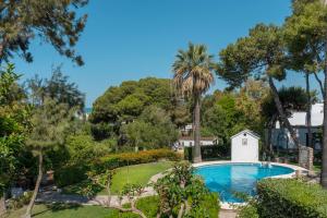 einen Pool in einem Garten mit Bäumen und einem Haus in der Unterkunft Suites Cortijo Fontanilla in Conil de la Frontera