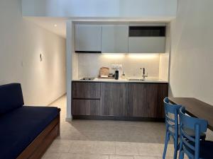 a kitchen with a sink and a counter with blue chairs at Zouzoulas Filoxenia - Koralia Apartments in Mil&iacute;na