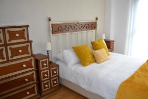 ein Schlafzimmer mit einem weißen Bett und gelben Kissen in der Unterkunft Ventanal de Saras Petfriendly Garaje Trastero y Chimenea - Arafita Apartamentos in Panticosa