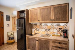 a kitchen with wooden cabinets and a black refrigerator at Myrtilli Cottages Pelion in Áno Lekhónia +28 photos