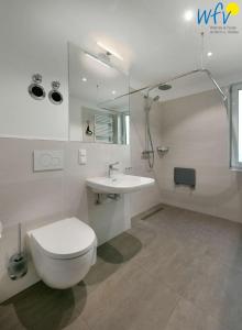 a white bathroom with a toilet and a sink at Haus am Hövt - Ferienwohnung 11 in Göhren