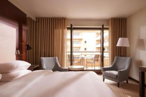 a hotel room with a bed and two chairs and a balcony at Hyatt Regency Nice Palais de la Méditerranée in Nice