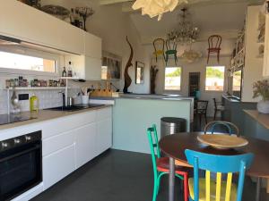 Una cocina con gabinetes blancos y una mesa y sillas. en Duplex avec terrasse vue mer et parking, en La Ciotat
