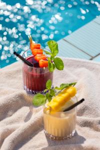 two cocktails on a table next to a pool at Astoria Resort in Riva del Garda