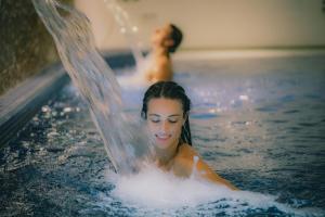 a woman in a swimming pool with a man in the background at Astoria Resort in Riva del Garda