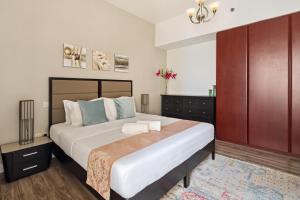 a bedroom with a large bed and a cabinet at La Buena Vida Holiday Homes - Modern, Luxe & Spacious 4-Bed, Full Kitchen, near to Beach, Tram & Marina in Dubai