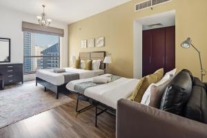 a hotel room with two beds and a couch at La Buena Vida Holiday Homes - Modern, Luxe & Spacious 4-Bed, Full Kitchen, near to Beach, Tram & Marina in Dubai +61 photos