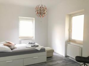 a white bedroom with a bed and two windows at Hollabrunn-Rest-Relaxation-Garden contactless check-in in Hollabrunn