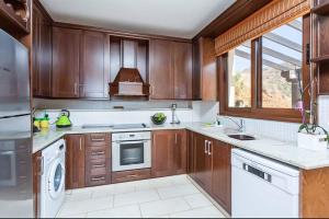 a kitchen with wooden cabinets and white appliances at Mermaid Villa in Pomos
