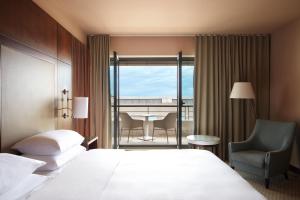 a bedroom with a bed and a chair and a balcony at Hyatt Regency Nice Palais de la Méditerranée in Nice