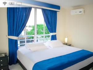 a bedroom with a bed with blue curtains and a window at Hotel Oasys Blue in Roldanillo +36 photos