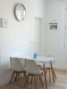 Una mesa de comedor con sillas y un reloj en la pared. en T2 au centre de Saint-Palais-Sur-Mer, en Saint-Palais-sur-Mer