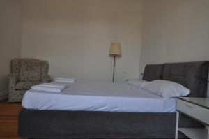 a bed in a room with a chair and a couch at Valentin Home Lesa in Lesa