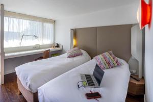 a hotel room with two beds with a laptop on it at Noemys ARLES in Arles