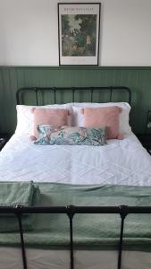 a bed with pink and white sheets and pillows at City Cottage in Lincoln