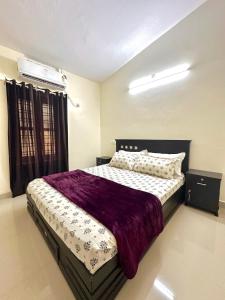 Un dormitorio con una cama grande con una manta morada. en Spacious Beach Side House - Joyce Cottage Kerala, en Trivandrum