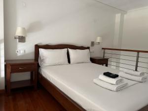 a bedroom with a bed with towels on it at Zouzoulas Filoxenia - Koralia Apartments in Mil&iacute;na