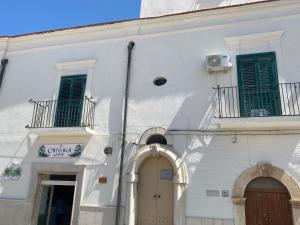 a white building with green shuttered windows and doors at Dimora Piazza Imperiale in Poggio Imperiale