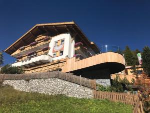 a building with a balcony with flowers on it at Wellness Residence Panorama - check-in at Olympia Hotel in Arabba