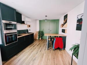 a kitchen with black cabinets and a wooden table at Time Travel in Saint-Rambert-sur-Loire