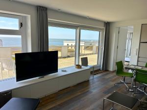 a living room with a flat screen tv and a view of the beach at Kalfamer Kalfamer 43 in Norderney