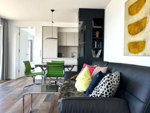 a living room with a black couch and green chairs at Kalfamer Kalfamer 43 in Norderney