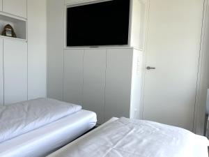 a bedroom with a bed and a flat screen tv at Kalfamer Kalfamer 43 in Norderney +10 photos